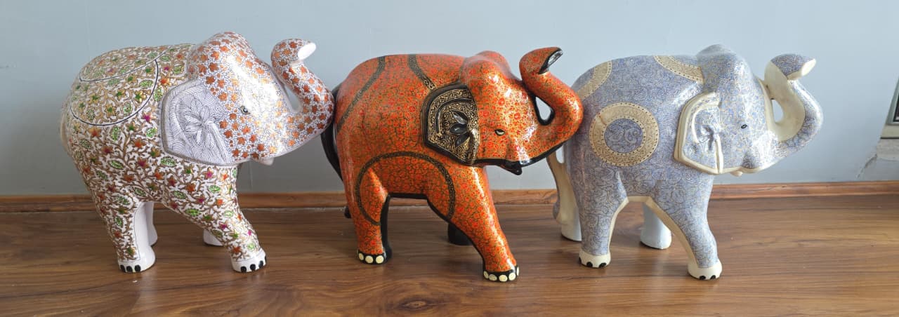 A row of hand-painted Kashmiri paper-mache elephants in graduated sizes